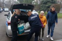 Uczniowie i policjant wkładają do bagażnika radiowozu dary dla schroniska zwierząt