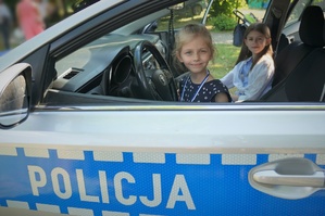 W policyjnym radiowozie siedzą dwie dziewczynki. U dołu zdjęcia widać napis POLICJA na drzwiach radiowozu